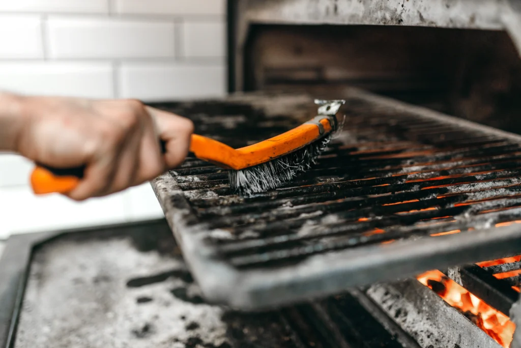 Person cleaning a Traeger grill with a brush