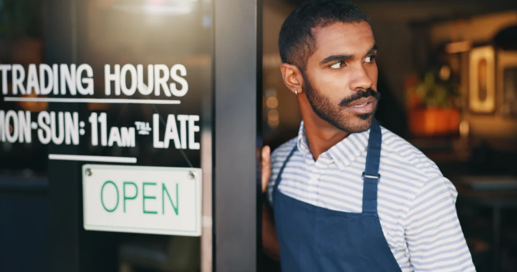 Man, coffee shop and open sign on front door with waiting for customer