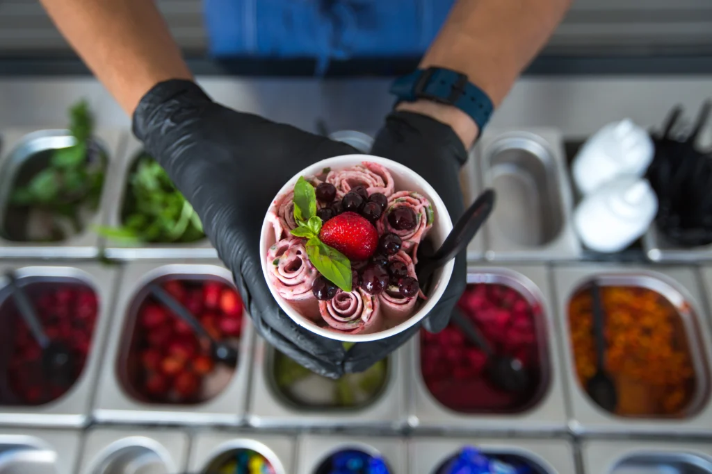 Hands holding a cup of rolled berry ice cream, illustrating results from the Ninja Creami. Is it just a glorified blender for frozen desserts?